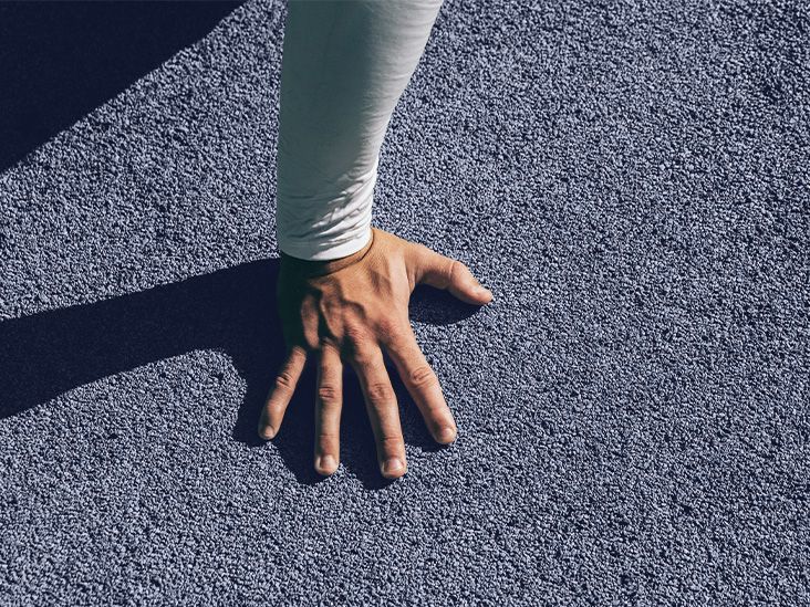 A hand is placed on a textured floor