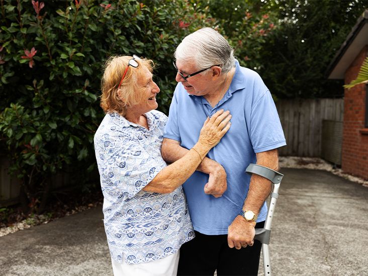 An older woman and man stand outside their home