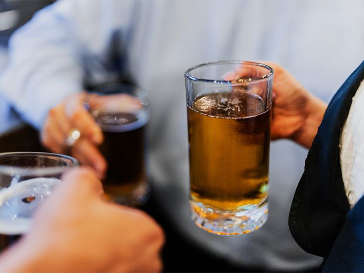 Glasses of beer are held by three people