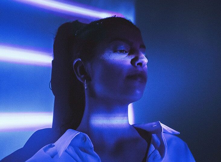 Young female sits under blue light