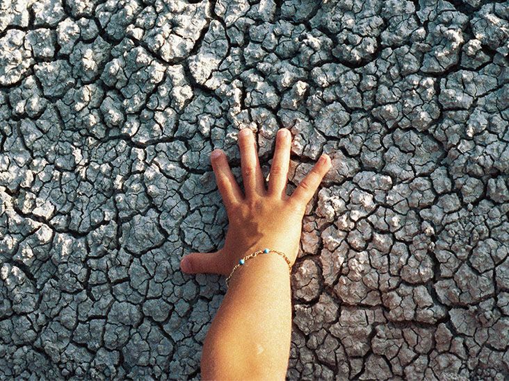 A hand presses against some dry, cracked ground
