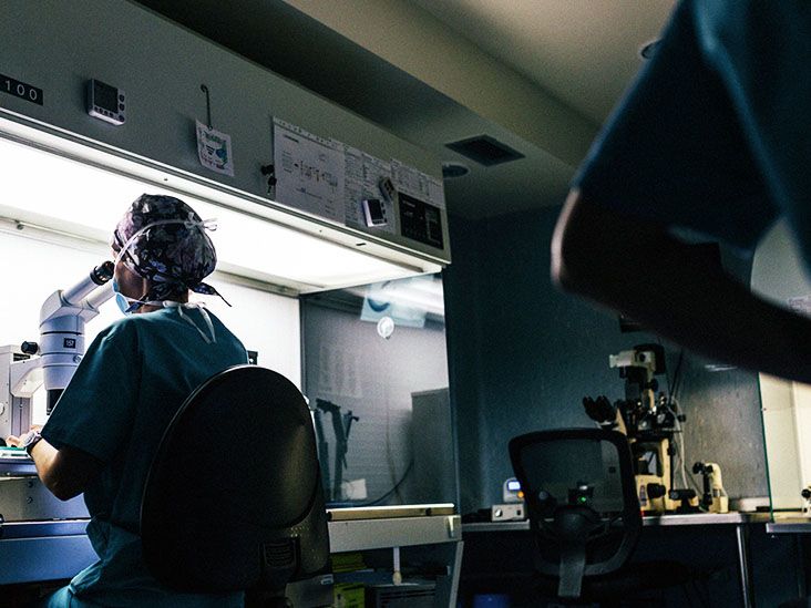 Scientist in lab examining cancer cells through microscope