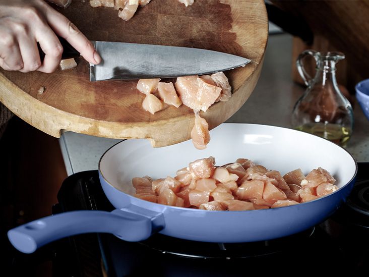 A person cooking diced chcicken breast in a pan, which is a good source of vitamin B
