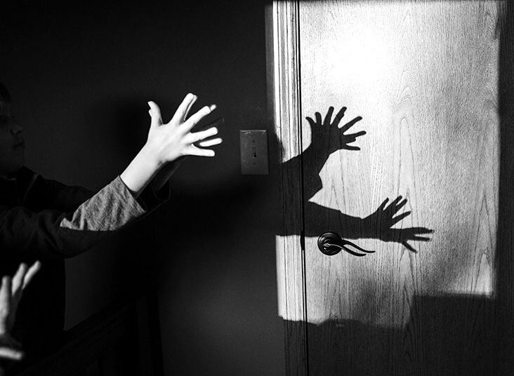 Children display hand shadow puppets on a wall