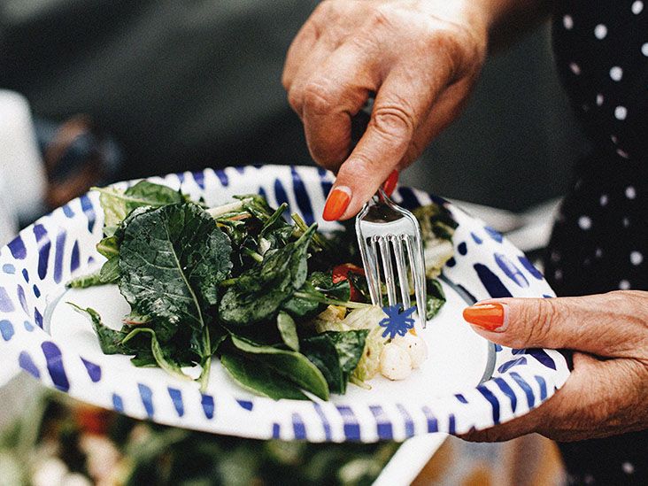 One older adult eating a salad rich in fiber on a paper plate