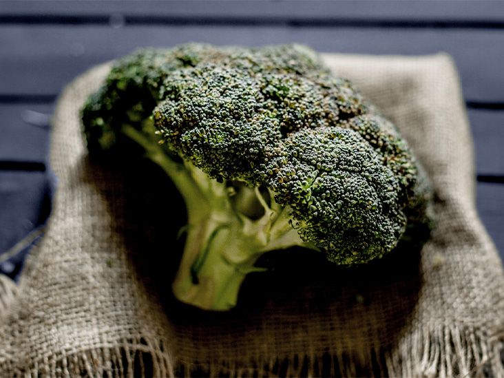 A piece of broccoli on a cloth on a flat surface