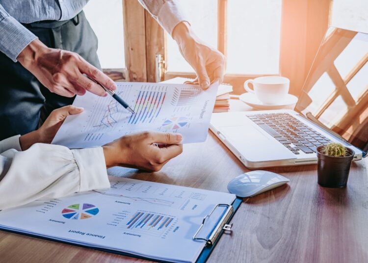 Business team analyzing income charts and graphs with modern laptop computer