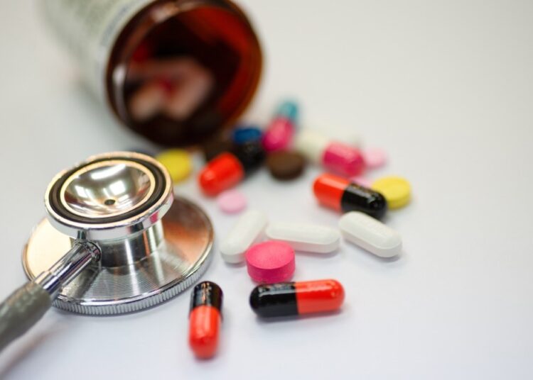 Close up of statin and beta-blocker pills and capsules with bottle and stethoscope