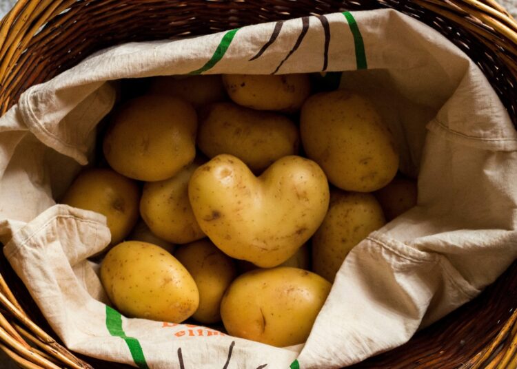 Heart shaped potato in a basket that full of potatoes.