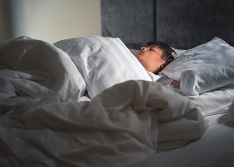 A boy sleeps in his bed.
