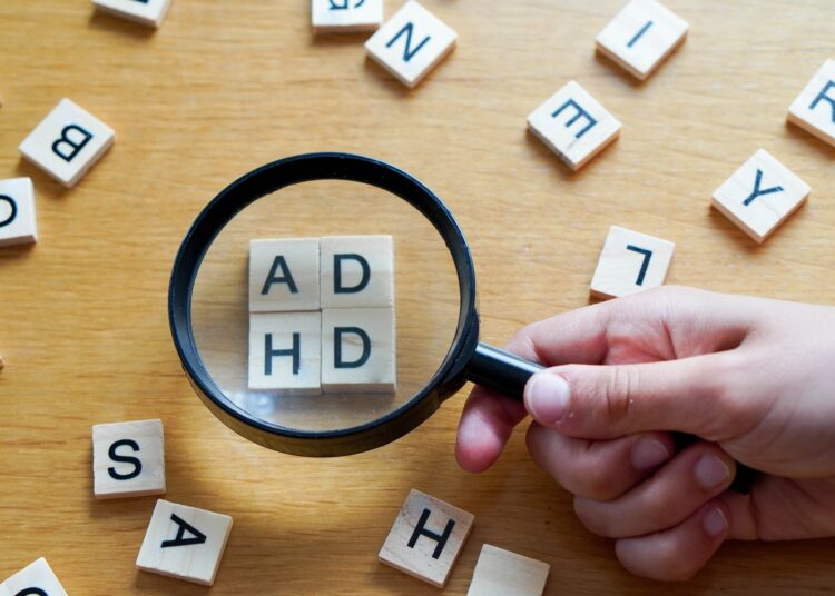 magnifying glass with wooden letters ADHD.