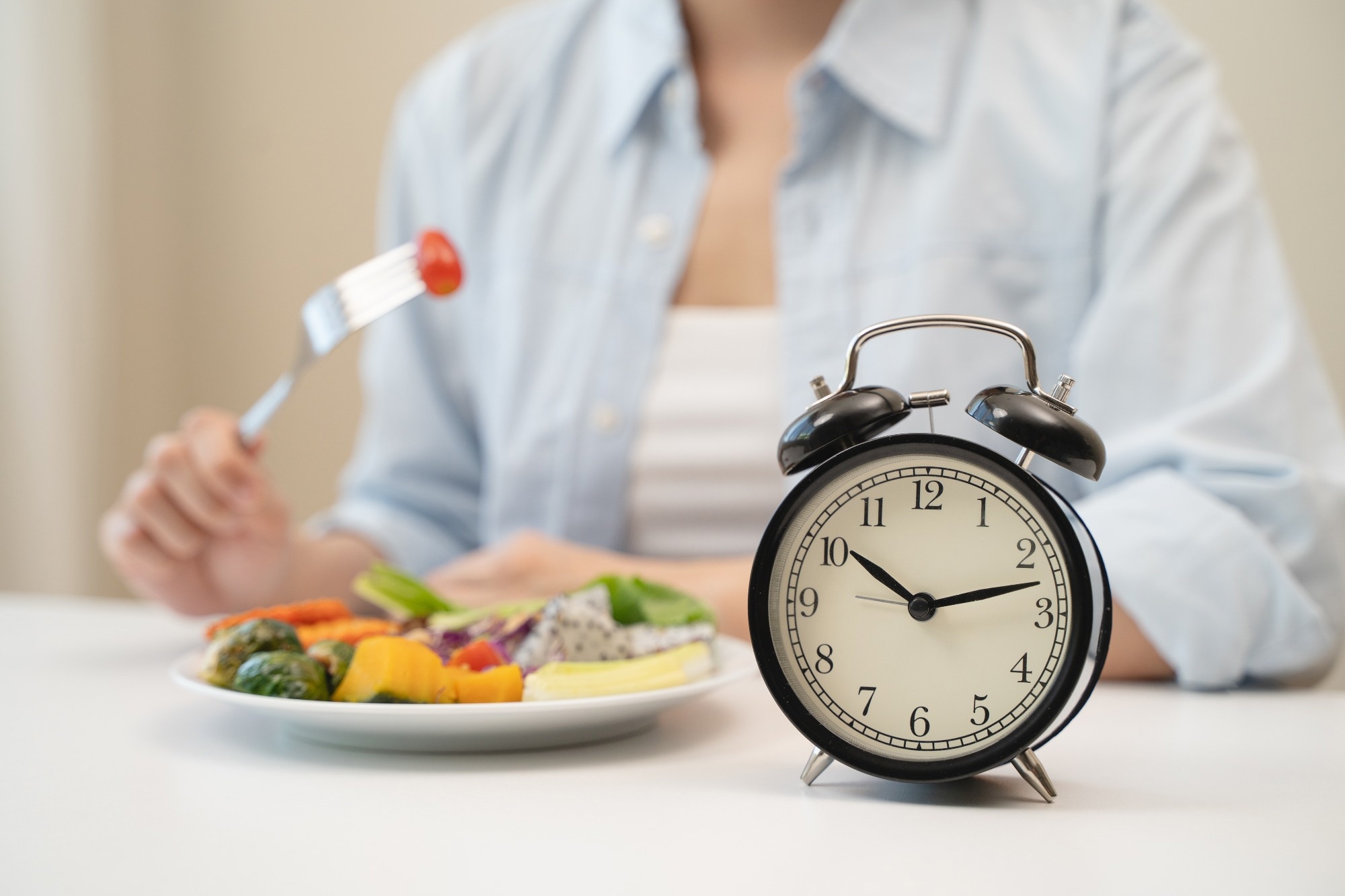 Intermittent fasting concept, Close-up on clock and people feeling hungry waiting time to eat during intermittent fasting diet session.