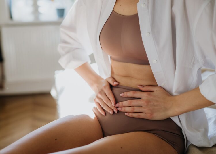 Woman at home suffering from menstrual pain, having cramps.