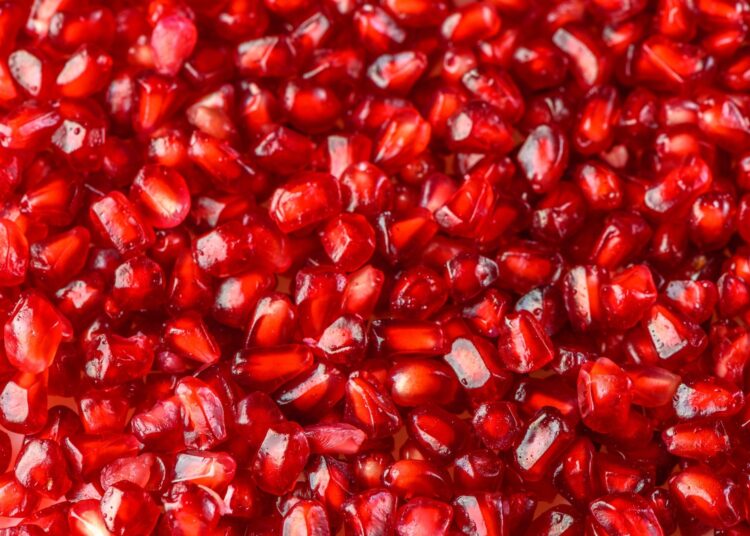 Delicious red ripe juicy pomegranate seed background texture.