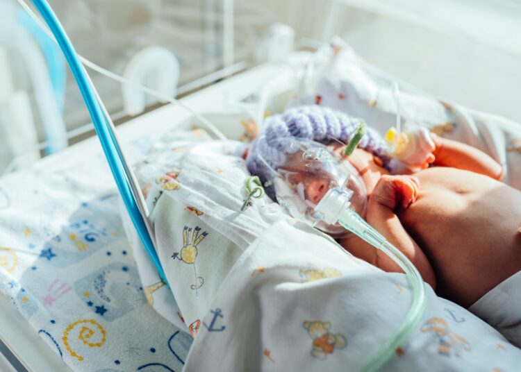 Small newborn child lies in pressure chamber connected to an artificial respiration apparatus