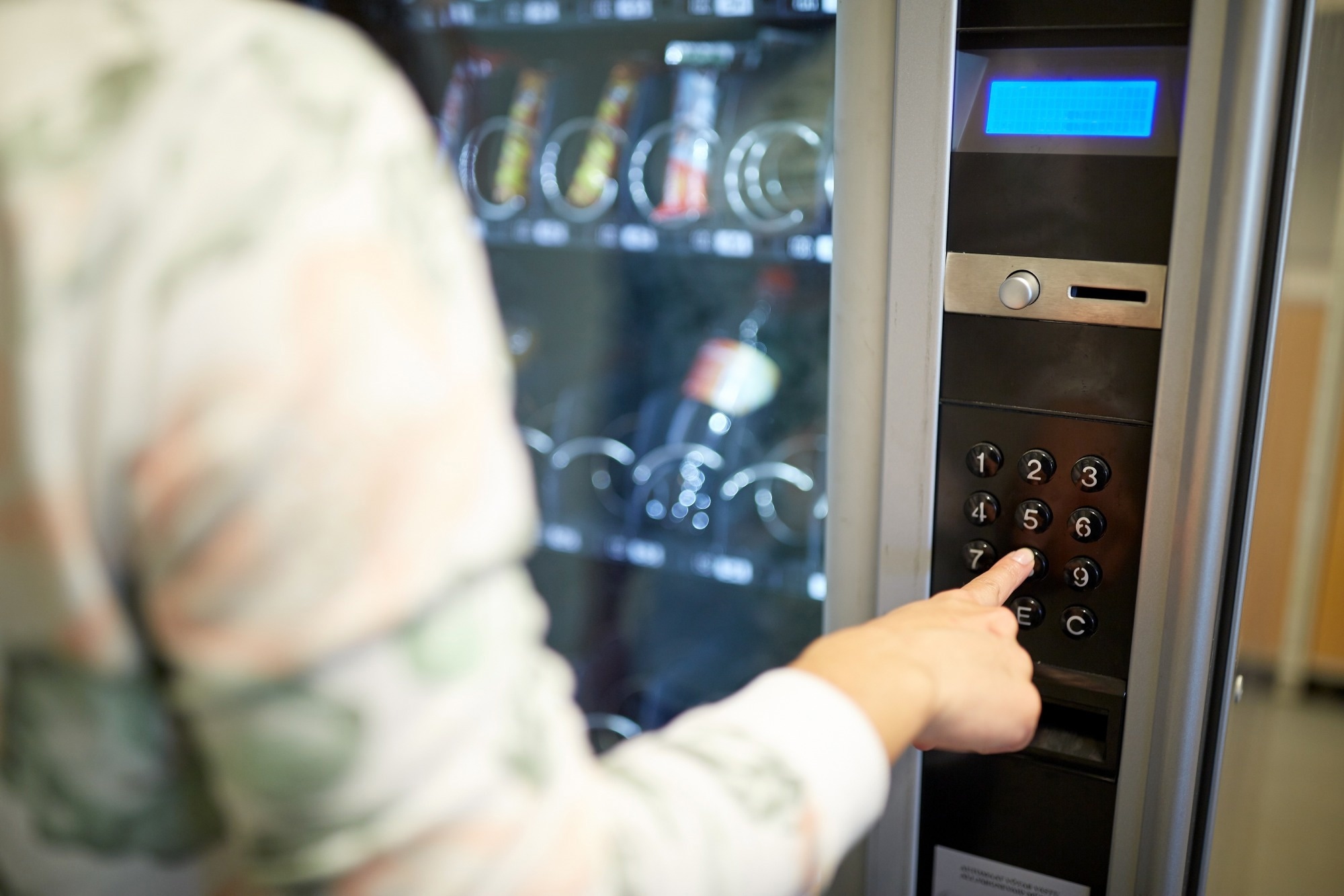 hand pushing button on vending machine operation panel keyboard