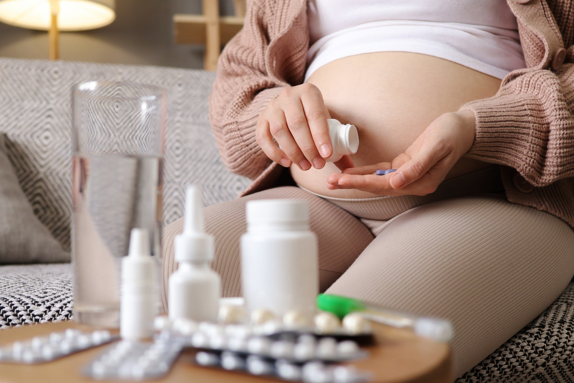 pregnant woman holding plastic jar with pills taking vitamins and minerals