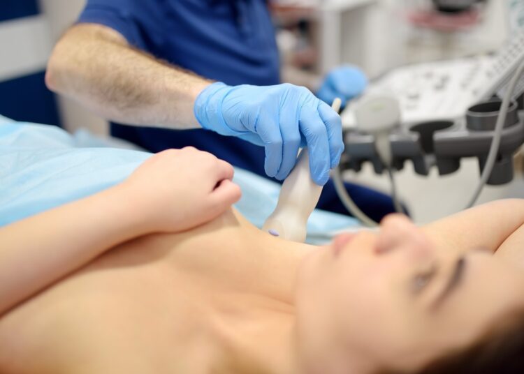 Mammologist doctor examines a woman breasts and lymph nodes using ultrasound
