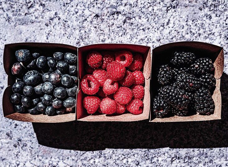 Blueberries, strawberries, and blackberries in three carton containers side by side