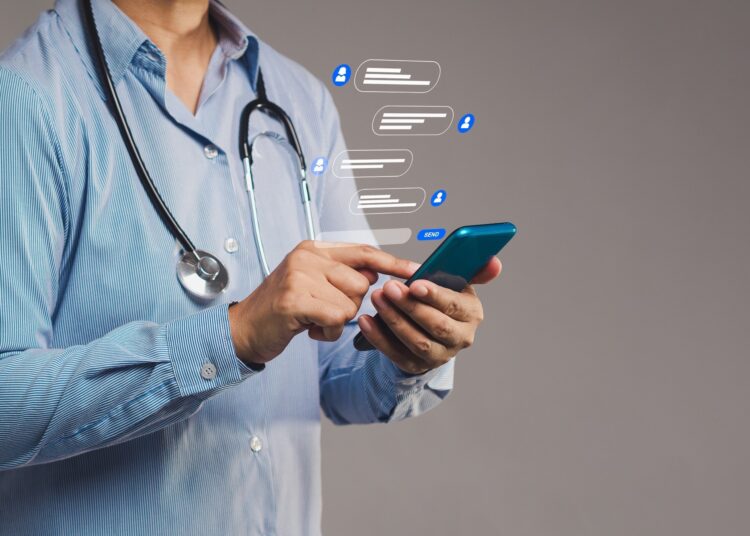 Close-up of a doctor interacting with smartphone, showing messaging symbols for online healthcare