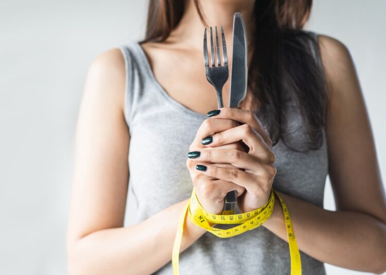 Woman holding a knife and for with hands tied together with a tape measure