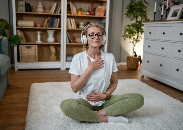Elderly woman sat on floor doing simple exercise and taking deep breath