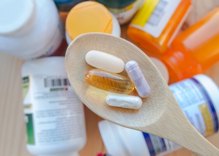 supplements and vitamins are in a wooden spoon