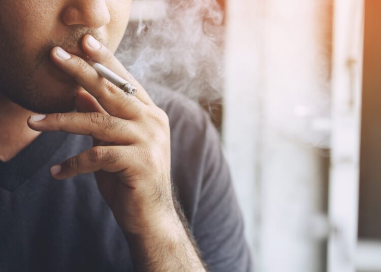 man holding smoking a cigarette in hand