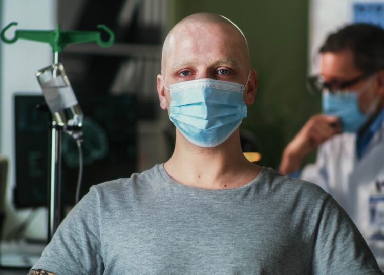 Bald man with cancer wearing mask and looking at camera