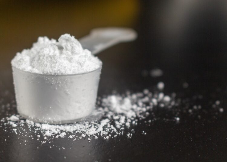 Creatine powder in a measuring scoop