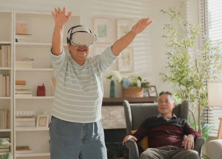 Older adult couple in living room. Woman using VR experience to do gentle exercise movement