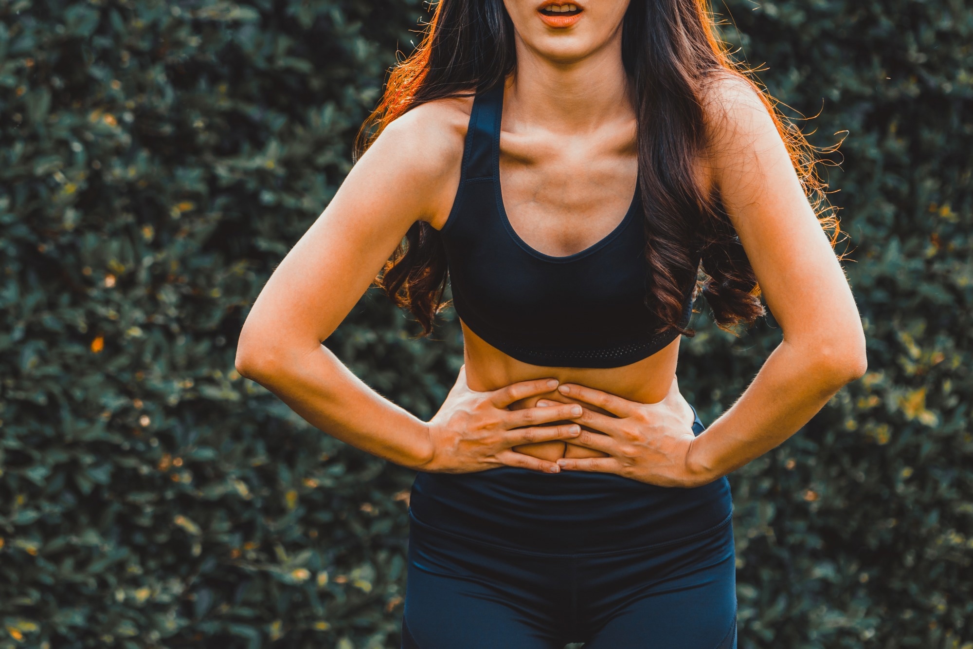 Young sport woman having pain at her stomach.
