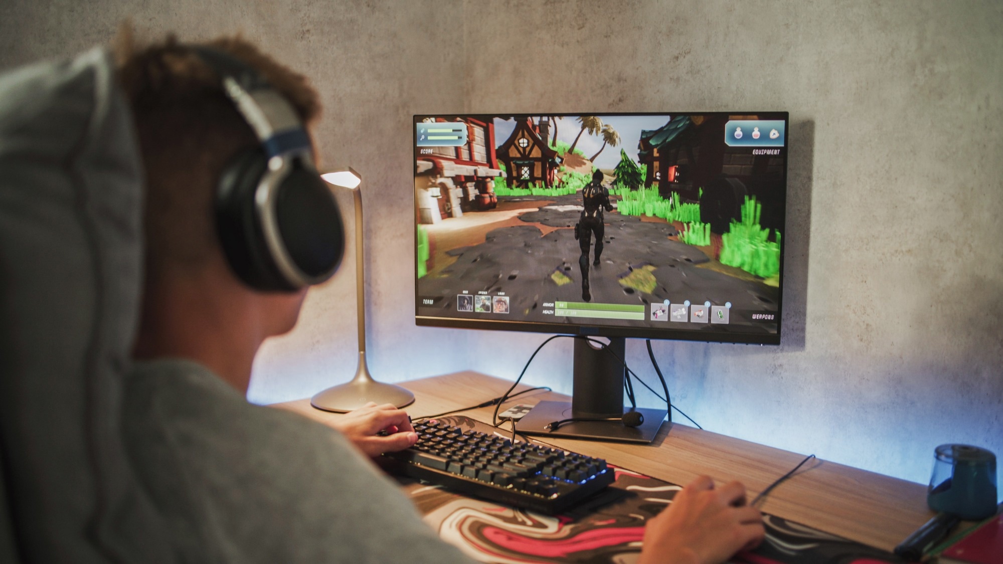 Caucasian teenager wearing headphones plays online video game on PC, spends leisure time at home.