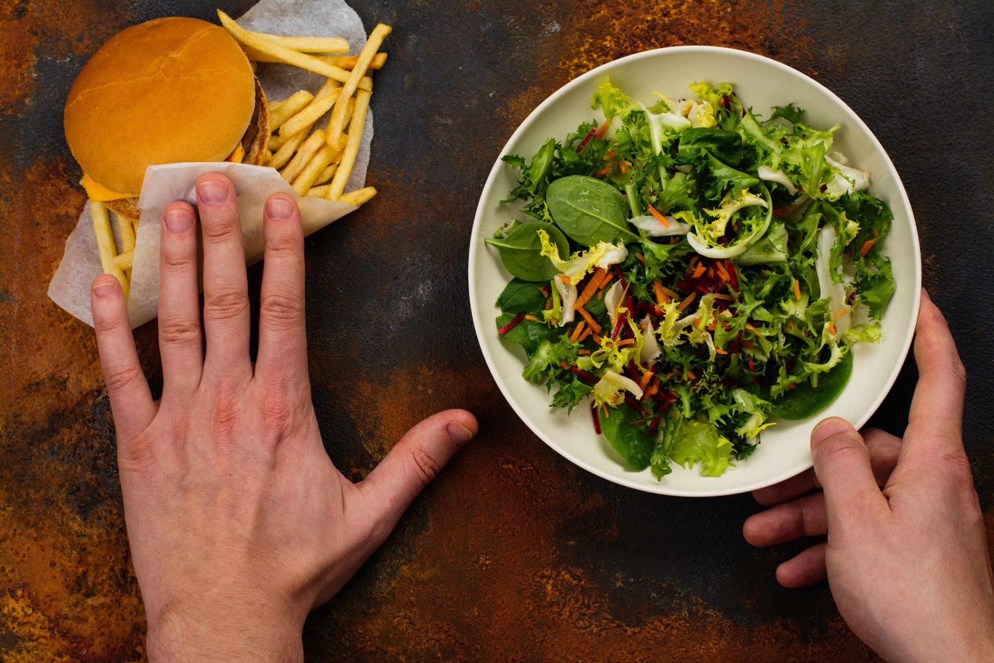 Jeune homme faisant le choix entre la salade et la restauration rapide