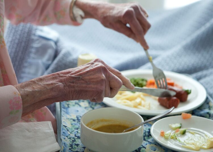 Elderly lady eating healthy lunch in bed.