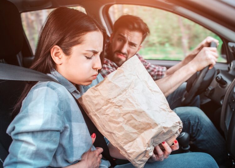A picture of sick girl holding a bag and trying to vomit into it