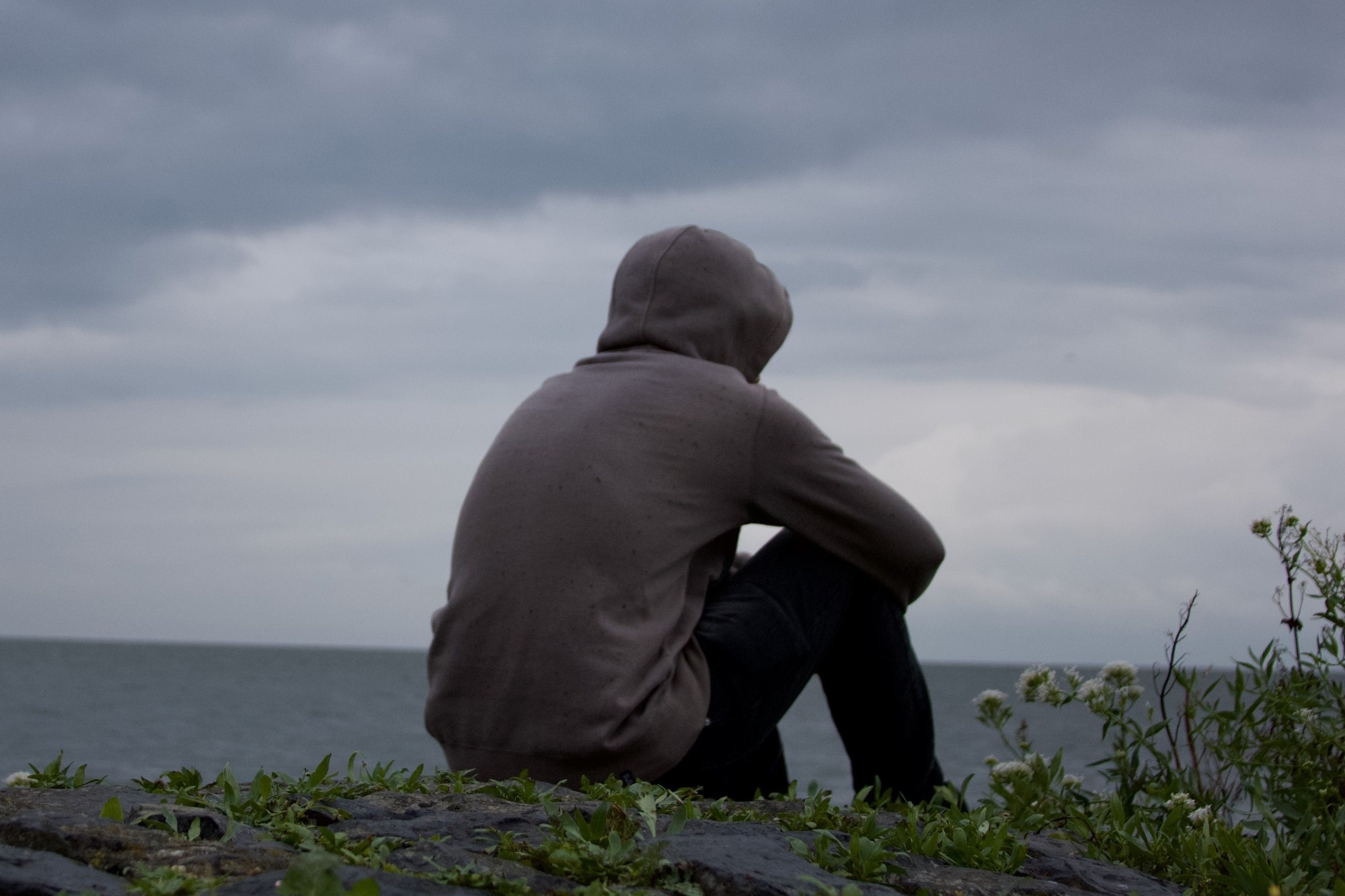 oneliness, a man looking towards the ocean during a cloudy weather