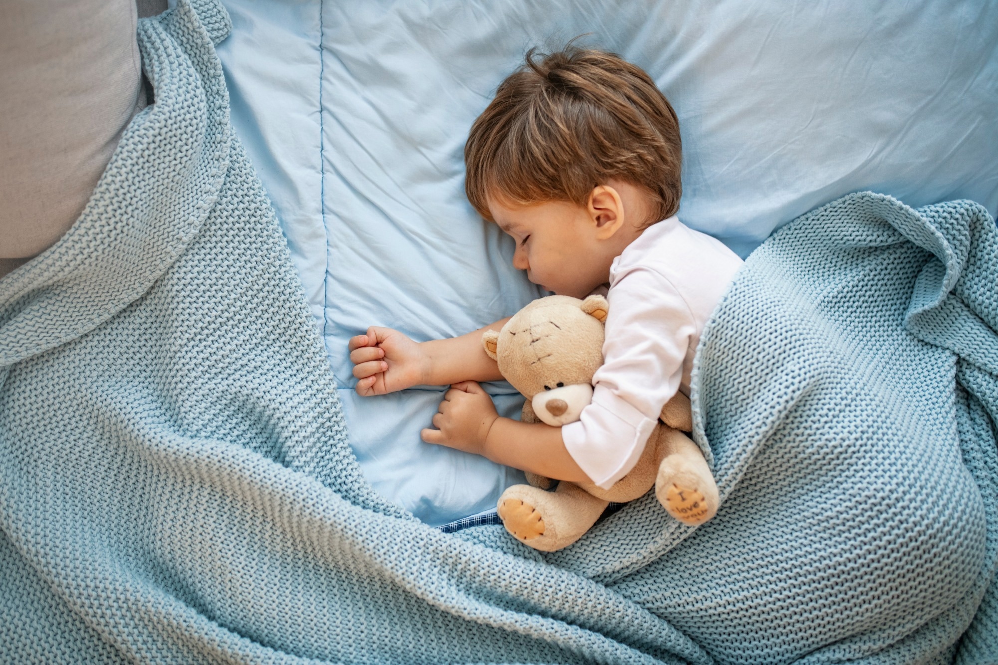 Photo of young boy sleeping together with teddy bear.