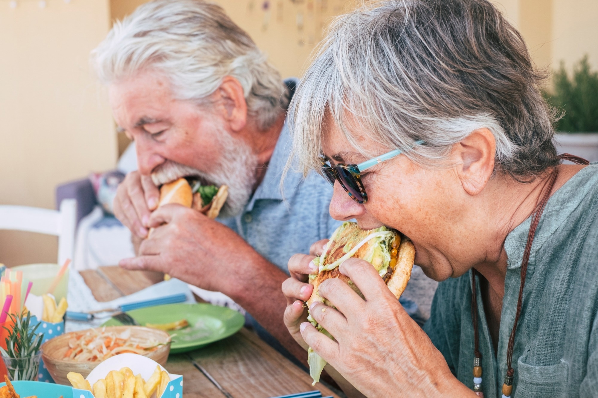 Couple of senior man and woman eating burgers