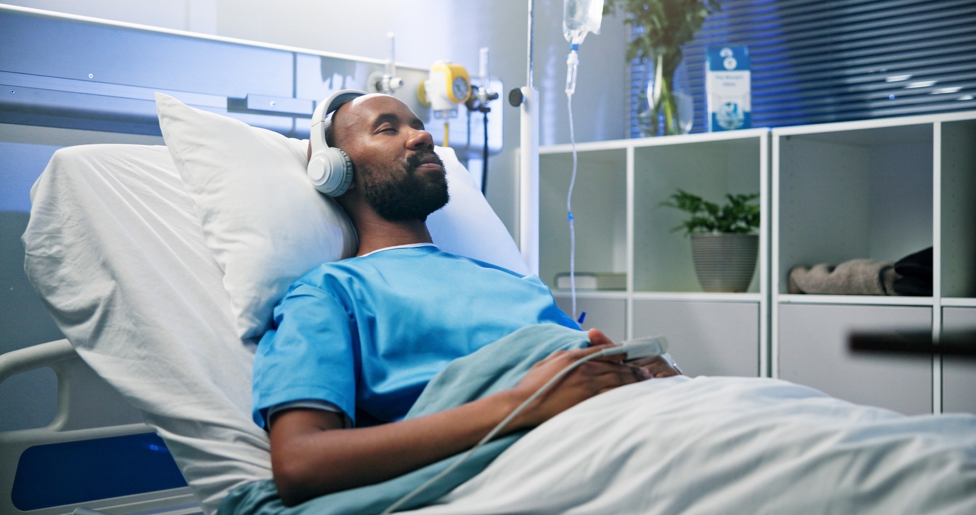 Black man, relax and sleep with headphones in hospital bed