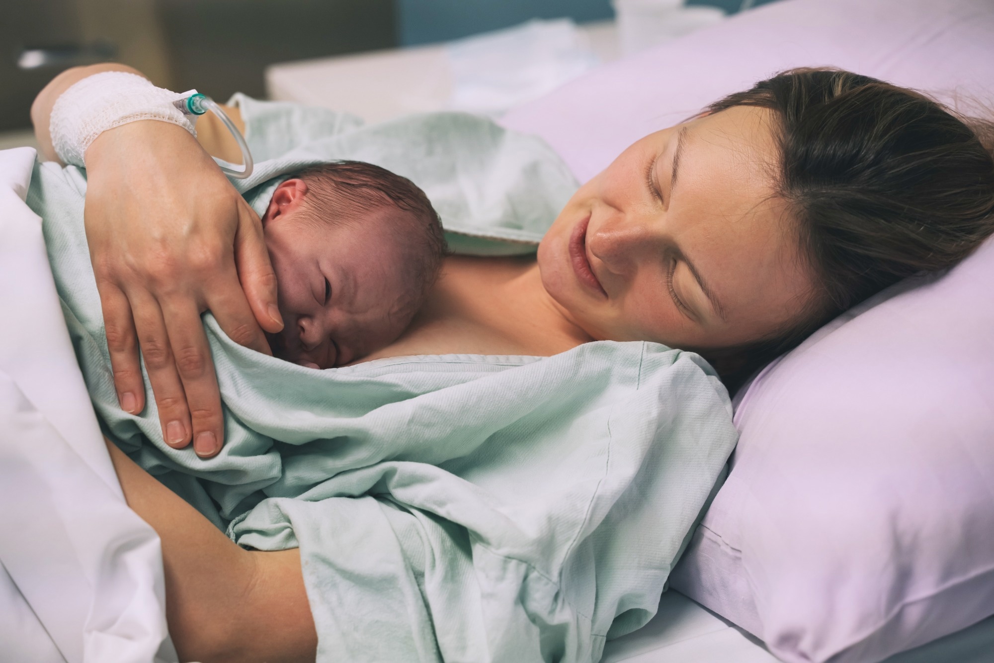 Young mom hugging her newborn baby after delivery.