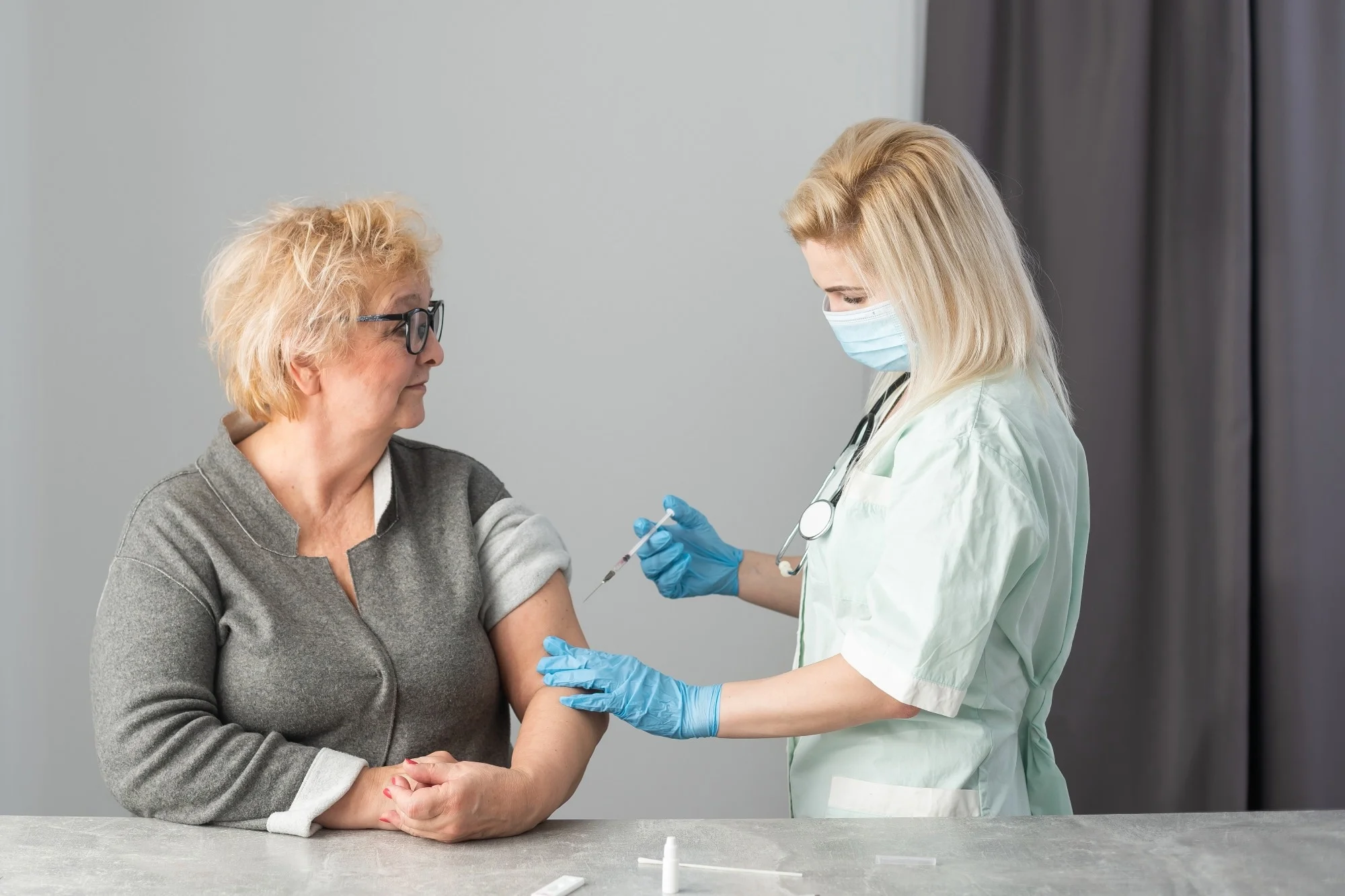 Older adult getting immune vaccine in arm for flu shot in hospital by nurse.