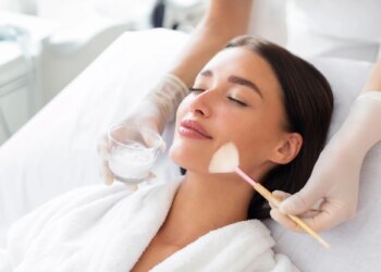 Cosmetologist cleaning face of a woman with special gel. Facial skin care procedures in beauty salon