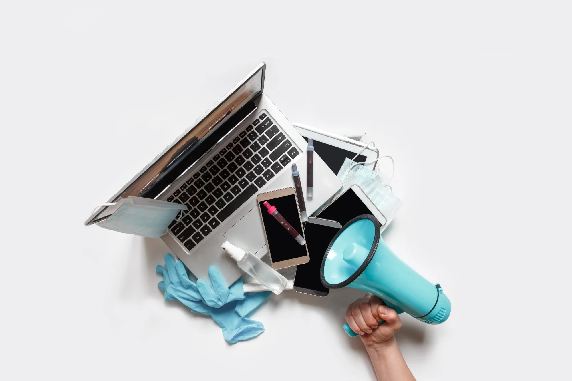Hands holding a tray with digital gadgets. Laptop. Phone from which they broadcast information. Hand with megaphone to the right
