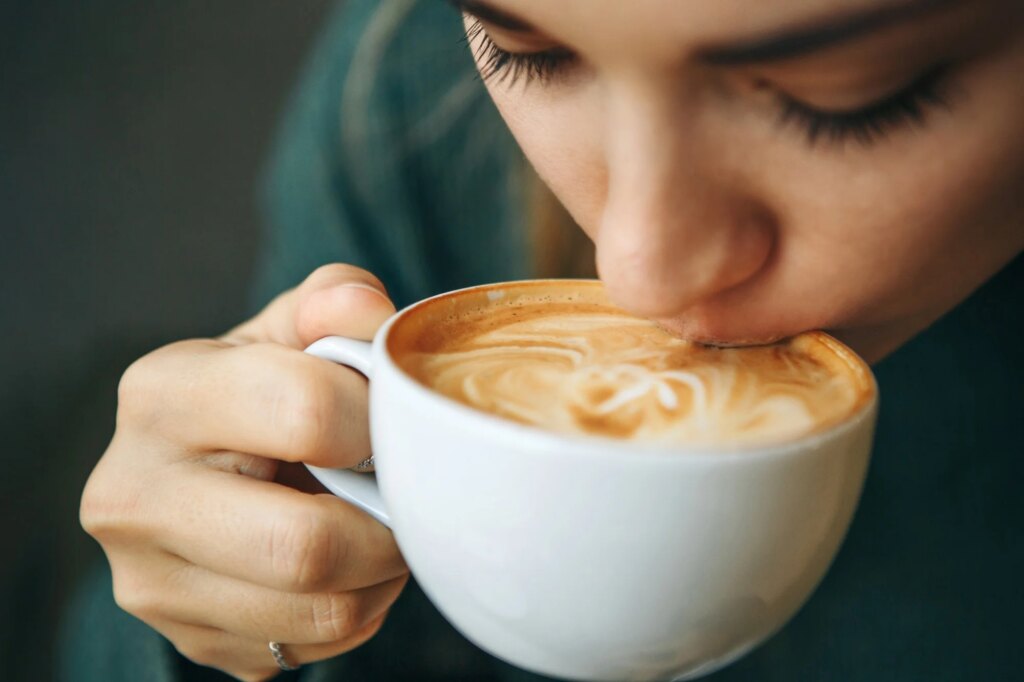 Close up girl is drinking coffee. She enjoys her morning cappuccino or flat white.
