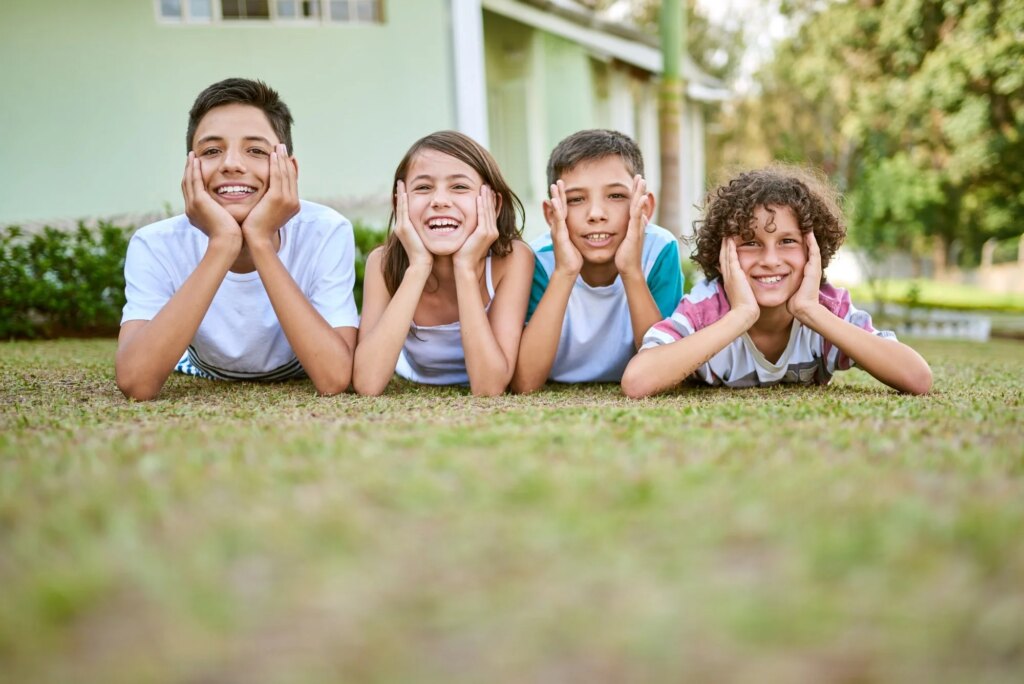 Portrait of a group of happy siblings lying together on the grass in their backyard.