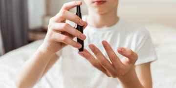 Teen boy takes a blood sample for diabetes with lancet pen. Problems of diabetes and insulin resistance in childhood