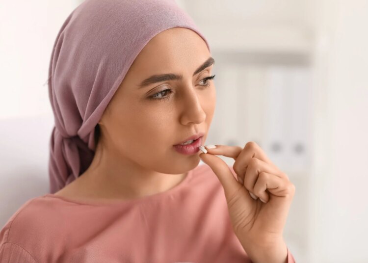 Young woman after chemotherapy taking pill in clinic, closeup