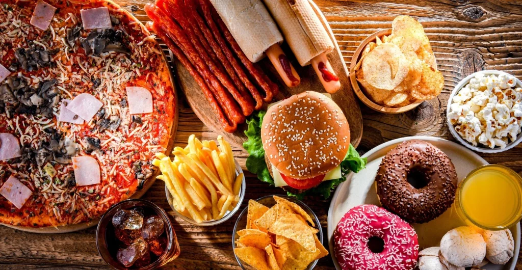 Ultra processed foods commonly associated with increasing the risk of cancer including pizza, fries, hot dogs, burger, popcorn and donuts
