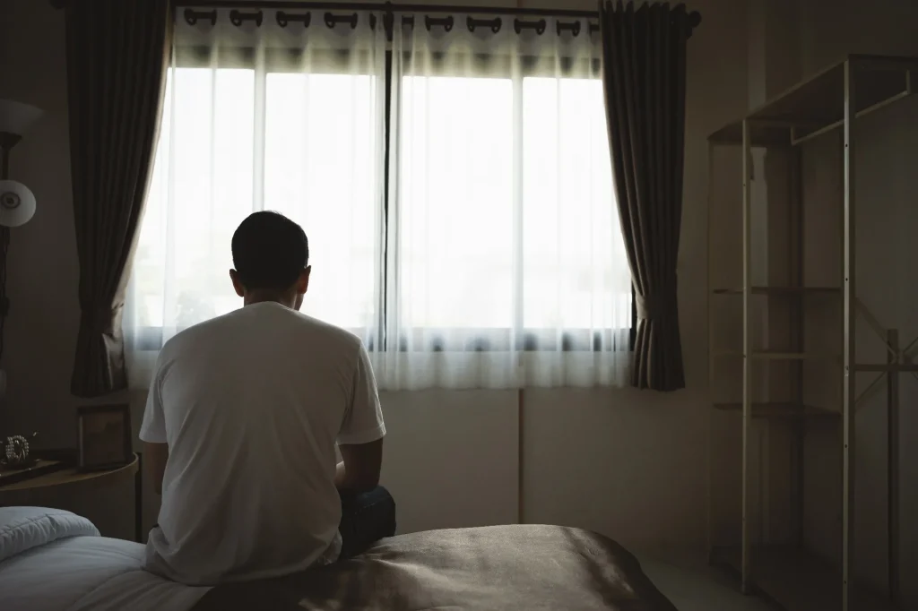 Silhouette depressed man sadly sitting on the bed in the bedroom.